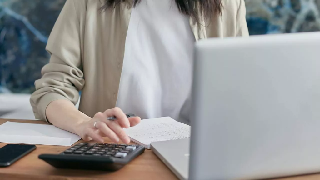 Kobieta siedzi przy stole i w zamyśleniu pisze w notatniku, analizując swoje myśli.